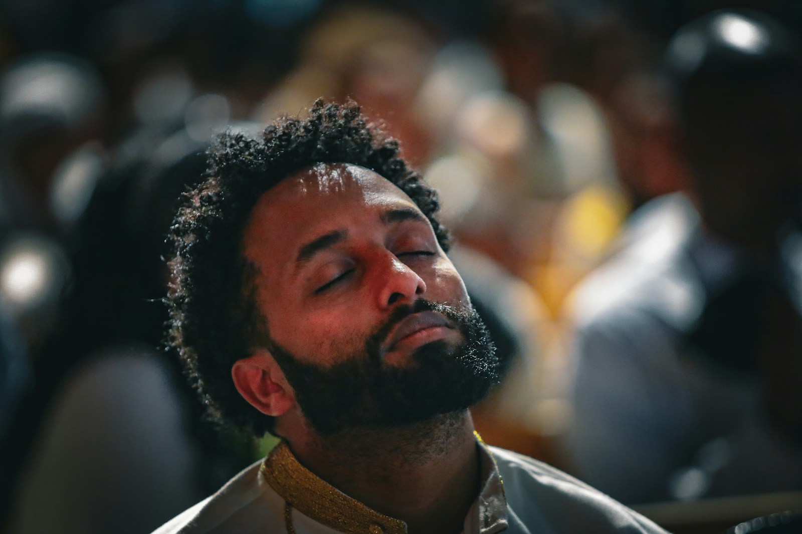 A man closes his eyes, bathed in sunlight.